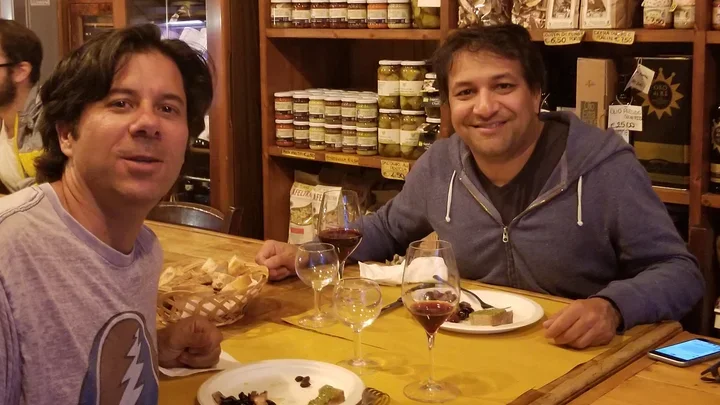 Anis and Carlos sitting at a table eating dinner in Italy.