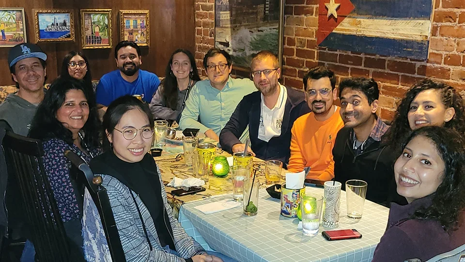 A group of people sit around a dinner table in a cozy restaurant with brick walls and Cuban decor.