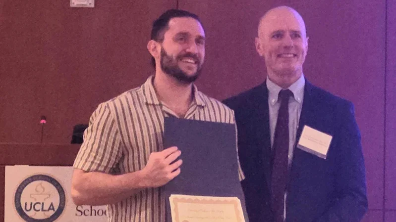 Carlos Sanchez and Tom holding an award and smiling. 