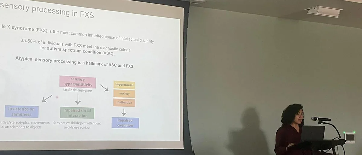 Irma Tello stands at front of room giving research presentation at neurobiology retreat, May 2024.