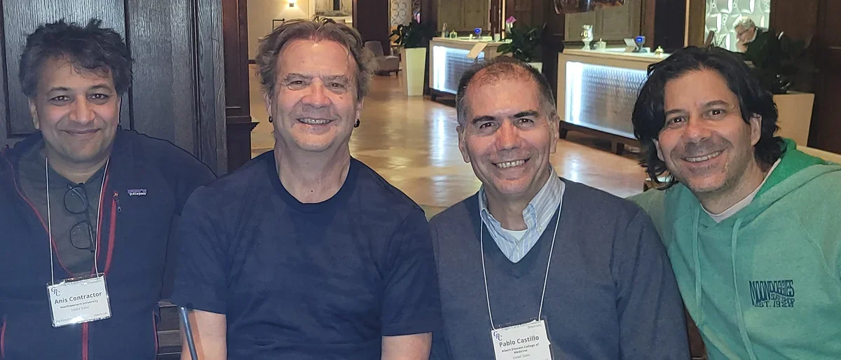 Dr. Portera smiling with group of male researchers at GRC conference, May 2024.
