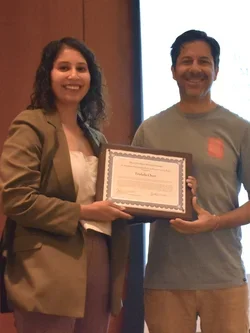 Trish and Carlos smiling holding an award in October 2023. 