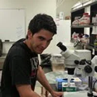Ricardo Rosales in lab with microscope.